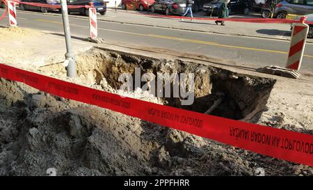 Belgrad, Serbien - 24. Januar 2020. Eine große Grube im Zentrum von Belgrad. Männer bei der Arbeit. Zerstörter Asphalt. Der mit Bürokratie umschlossene Standort für die Verlegung oder Reparatur unterirdischer Rohre. Städtische Infrastruktur Stockfoto