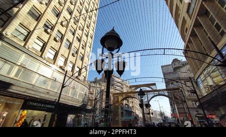 Das Zentrum der Großstadt. Fußgängerzone für Touristen. Ansicht von oben nach unten mit Weitwinkel. Vor dem Hintergrund von Häusern und dem blauen Himmel, eine große Straßenlampe, Drähte und Girlanden. Riesige Gebäude Stockfoto