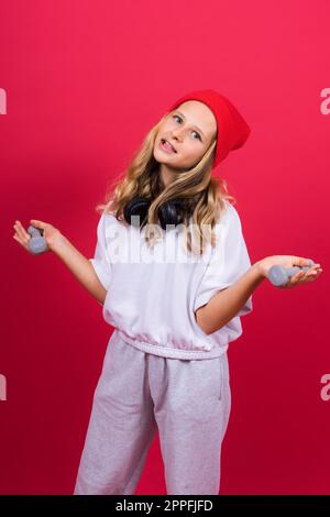 Ein Mädchen, das Fitnessübungen mit Kurzhanteln auf rotem Hintergrund macht Stockfoto