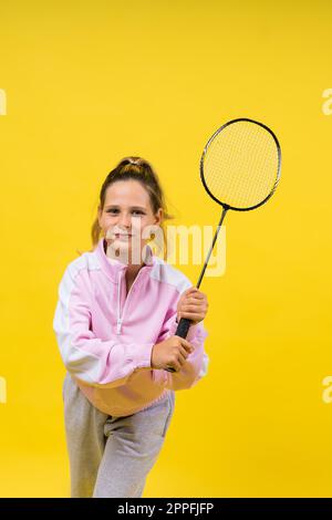 Studio-Foto von einem zehnjährigen Mädchen mit Badminton-Schläger, isoliert auf Gelb. Stockfoto