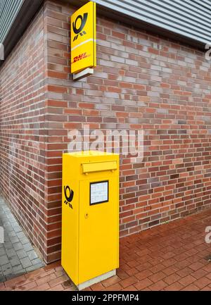 Kiel, Deutschland - 07. Juli 2022. Ein gelber deutscher Postkasten an einer roten Backsteinmauer mit einem deutschen Postschild darüber. Stockfoto