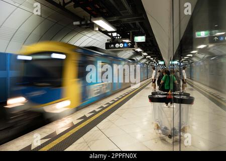 Die U-Bahn kommt an einem unterirdischen Bahnsteig an, spiegelbildlich im Glas. Metro Melbourne ist das größte Nahverkehrsnetz Australiens Stockfoto