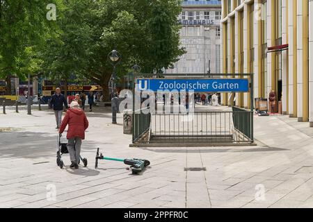Liegender E-Scooter und ältere Frau an der U-Bahn-Station Zoologischer Garten am Breitscheidplatz in Berlin Stockfoto
