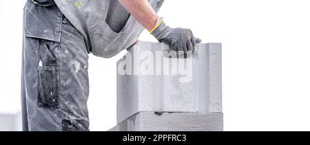 Ein Mauerwerk baut die Wand eines Gebäudes aus Betonziegeln und -Blöcken Stockfoto
