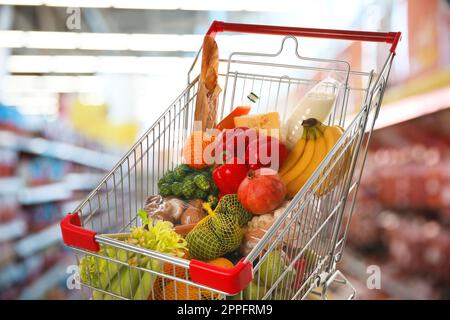 Einkaufswagen mit verschiedenen Lebensmitteln im Supermarkt Stockfoto