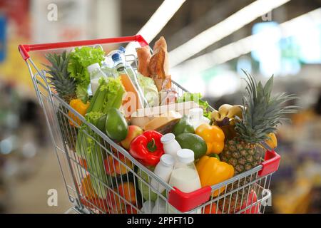 Einkaufswagen mit verschiedenen Lebensmitteln im Supermarkt Stockfoto