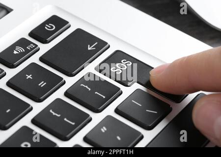 Frau drückt Knopf mit Wort SOS auf der Computertastatur, Nahaufnahme. Rettungskonzept Stockfoto