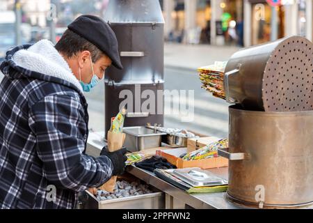 Straßenverkäufer von heißen Kastanien auf Holzkohle in Porto, Portugal Stockfoto