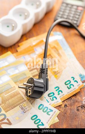 Elektrostecker und Euro-Geld auf Holztisch. Konzept steigender Strompreise. Stockfoto