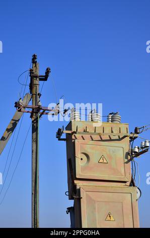 Alten und veralteten elektrischen Transformator vor dem Hintergrund eines wolkenlosen blauen Himmel. Gerät für die Verteilung der Energie mit hoher Spannung Stockfoto