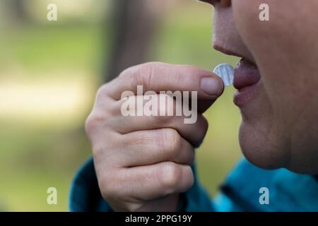 Eine Frau, die sich eine Pille auf die Zunge legt Stockfoto