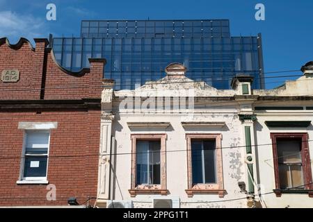 Historische verwitterte alte koloniale Fassaden im Vordergrund und ein modernes Glasgebäude im Hintergrund in Melbourne. Alt und Neu Stockfoto