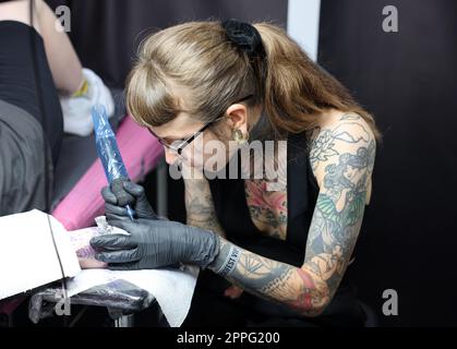 Nicht identifizierter Teilnehmer bei der 15. Tattoofest Convention in Krakau. Tattoo-Künstler bei der Arbeit. Stockfoto