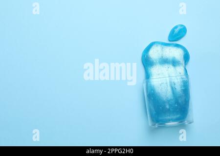 Umgedrehter Kunststoffbehälter mit hellem Schleim auf hellblauem Hintergrund, Draufsicht. Platz für Text Stockfoto