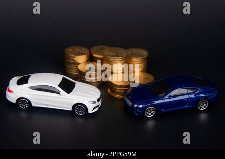 Kuala Lumpur, Malaysia - Juli 2022 : Miniatur-Spielzeugauto von Mercedes AMG und Bentley Continental GT mit Goldmünzen auf schwarzem Einband. Stockfoto