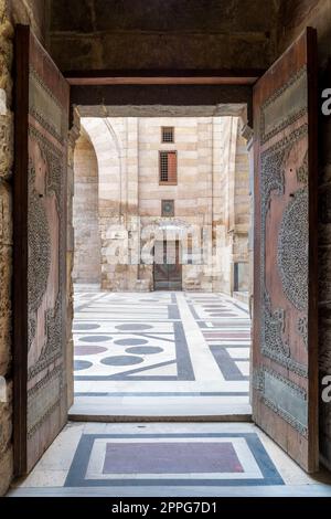 Geöffnete Tür führt zum Innenhof der Al-Sultan Al-Zahir Barquq Moschee, Alt-Kairo, Ägypten Stockfoto