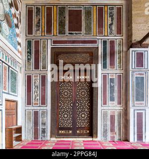 Alte, farbenfrohe Marmorwand mit Holztür, dekoriert mit arabischen Ornamenten, Kairo, Ägypten Stockfoto