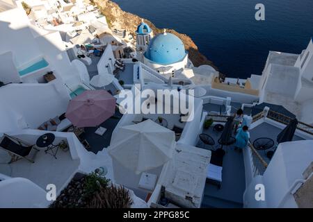 Blick vom Aussichtspunkt auf das Dorf Oia mit der blauen Kuppel der griechisch-orthodoxen christlichen Kirche und der traditionellen, weiß getünchten griechischen Architektur. Santorini, Griechenland Stockfoto