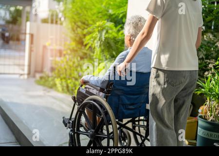 Pflegekraft helfen und pflegen asiatische Seniorin oder ältere Frau Patientin im Rollstuhl auf Rampe im Krankenpflegekrankenhaus, gesund stark medizinisches Konzept. Stockfoto