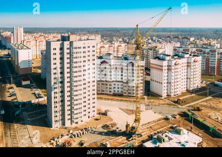 Gomel, Weißrussland. Der Baukran ist am Bau eines neuen mehrstöckigen Wohngebäudes beteiligt. Mehrstöckige Häuser Aus Der Vogelperspektive. Immobilien Hochhäuser. Entwicklungsindustrie. Stockfoto