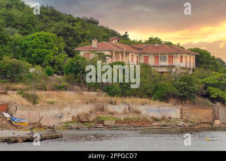 Altes verlassenes Haus auf den Hügeln der Insel Kinaliada in der Marmarameer, mit dichten Bäumen, bei Sonnenaufgang, Istanbul, Türkei Stockfoto
