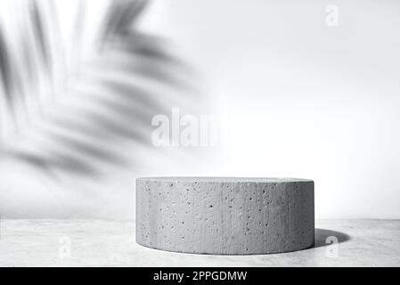 Betonpodiumsockel und Palmenblätter Schatten auf steingrauem Hintergrund, Kopierbereich. Anzeigevorlage für kosmetische Produkte oder Hautpflegeprodukte. Stockfoto