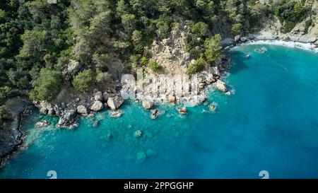 Ein unvergleichlicher Blick auf die Küste mit einem unberührten, blauen Gewässer mit zerklüfteten Felsen und verschiedenen Bäumen in der Türkei. Stockfoto