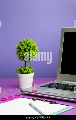 Laptop Mit Wichtigen Informationen Auf Dem Tisch Mit Pflanze Und Tasse Kaffee. Grausame Ankündigungen Auf Dem Computerbildschirm Am Schreibtisch Mit Blume Und Tasse. Stockfoto