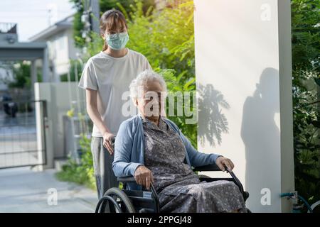 Pflegekraft helfen und pflegen asiatische Seniorin oder ältere Frau Patientin im Rollstuhl auf Rampe im Krankenpflegekrankenhaus, gesund stark medizinisches Konzept. Stockfoto