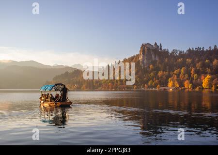 Traditionelles Holzboot auf dem wunderschönen Bleder See, Slowenien bei Sonnenuntergang. Stockfoto