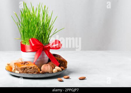 Novruz Tischdekoration, Weizengras, Baklava Gebäck und Nüsse. Arabischer Feiertag von Nowruz, Frühlingsfeier, Kopierraum. Stockfoto