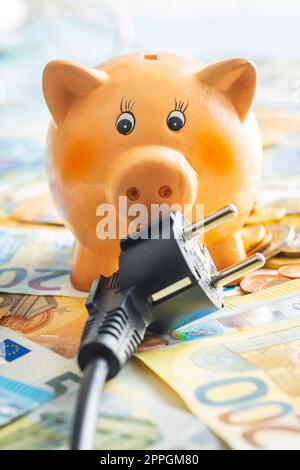 Elektrostecker, Sparschwein und Euro-Geld. Konzept steigender Strompreise. Stockfoto