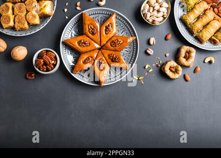 Arabisches Baklava mit Nüssen und Honig auf dunklem Hintergrund, Kopierbereich, Draufsicht. Ramadan Dessert - frisches Nussbaklava. Stockfoto