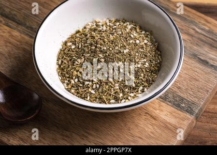 Gemischte Zaatar- oder Zatar-Gewürze in weißer Schüssel Nahaufnahme. Orientalische Kräutergewürze Zaatar oder Zattar. Arabische Küche. Stockfoto