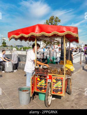 Junger Mann, der Kastanie und Mais auf einem traditionellen türkischen Fast-Food-Wagen an der Eminonu Piazza, Istanbul, Türkei verkauft Stockfoto