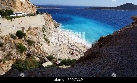 Von der Straße aus hat man einen tollen Blick auf die Menschenmassen, die sich am Strand entspannen. Menschen im Meer schwimmen. Draufsicht auf Kaputas Beach zwischen Kas und Kalkan Stockfoto