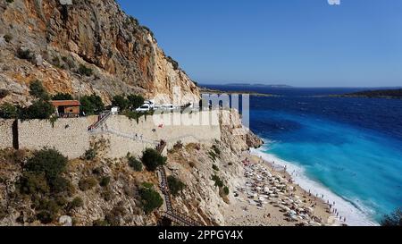 Von der Straße aus hat man einen tollen Blick auf die Menschenmassen, die sich am Strand entspannen. Menschen im Meer schwimmen. Draufsicht auf Kaputas Beach zwischen Kas und Kalkan Stockfoto