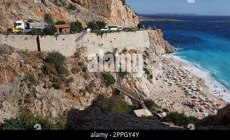 Von der Straße aus hat man einen tollen Blick auf die Menschenmassen, die sich am Strand entspannen. Menschen im Meer schwimmen. Draufsicht auf Kaputas Beach zwischen Kas und Kalkan Stockfoto