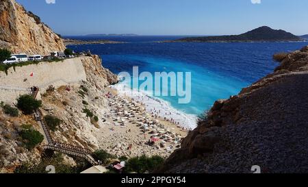 Von der Straße aus hat man einen tollen Blick auf die Menschenmassen, die sich am Strand entspannen. Menschen im Meer schwimmen. Draufsicht auf Kaputas Beach zwischen Kas und Kalkan Stockfoto