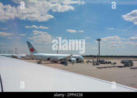 Flughafen Frankfurt Deutschland 02. August 2022 - Blick vom Flugzeugfenster auf einen Flügel und Blick auf eine beladene Air Canada Maschine Stockfoto