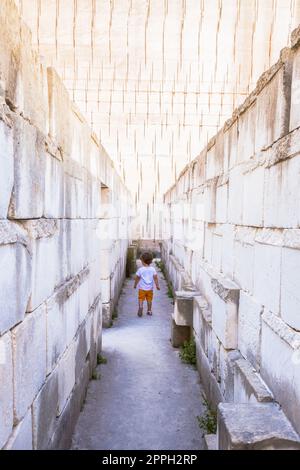 Kaukasisches junges Kind, das in einem Labyrinth läuft. Konzeptuelles Bild für gefährliche Situationen in der Kindheit. Stockfoto