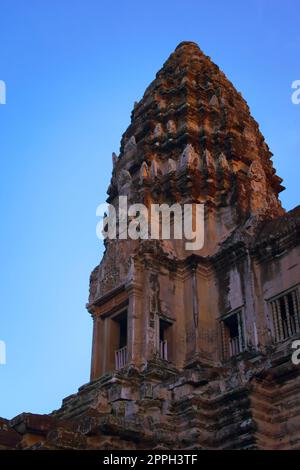 Angkor Wat, in Kambodscha. Niedriger Winkel Blick auf einen der zentralen Türme bei Sonnenuntergang vor blauem Himmel. Stockfoto
