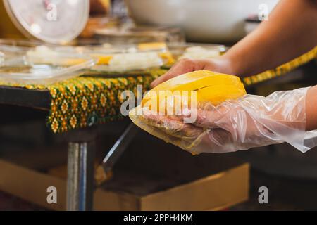 Eine Frau, die reife gelbe Mango von Hand schält. Stockfoto