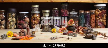 Meditationsaltar mit Steinkristallen und Blumen. Kräutergläser im Hintergrund Stockfoto