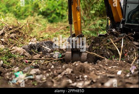 Baggerlader Graben von Erde auf der Baustelle. Schaufel mit Baggerladerboden zum Graben. Roden und Roden. Bagger auf Straßenbaustellen. Erdbewegungsmaschine. Ausgrabungsfahrzeug. Erschließung von Grundstücken. Stockfoto