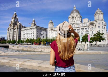 Urlaub Liverpool, Großbritannien. Schöne junge Frau, die Pier Head mit „The Three Graces“ im Stadtzentrum von Liverpool, England, besucht. Stockfoto