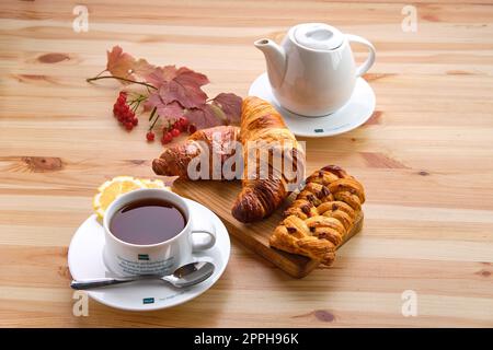 4. Oktober 2019, Minsk, Weißrussland: Blätterteiggebäck, Rosinenbrötchen und knusprige Croissants auf einem Holztisch mit Kaffee Stockfoto