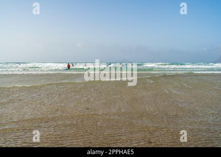 FAMARA BEACH LANZAROTE, KANARISCHE INSELN - 21. JULI 2022: Surfer auf den Wellen. Famara Beach (Playa de Famara), beliebter Surfstrand auf Lanzarote. Stockfoto