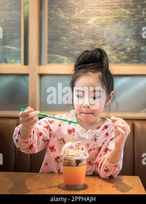 Hübsches asiatisches Mädchen, das Eisschokolade im Café trinkt, nimm einen Strohhalm Stockfoto