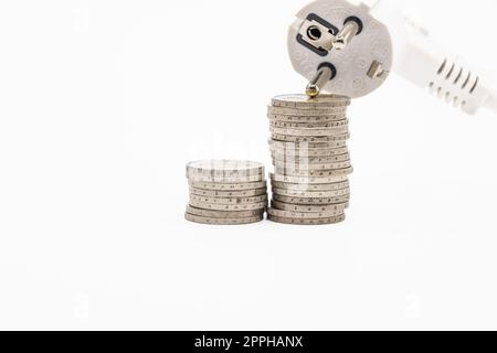 Stapel aufsteigender Münzen und elektrischer Stecker. Konzept der steigenden Strompreise Stockfoto